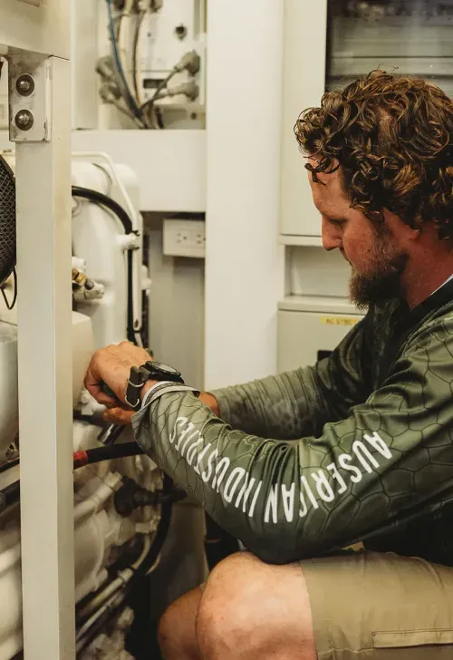 Image of Marcus Shubert, Master Marine Mechanic, working on a piece of marine equipment.