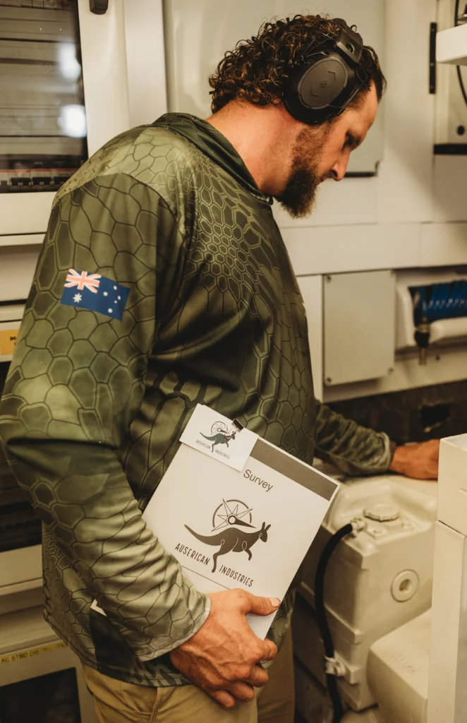 Image of Marcus Shubert, Master Marine Mechanic, surveying a boats engine room equipment.